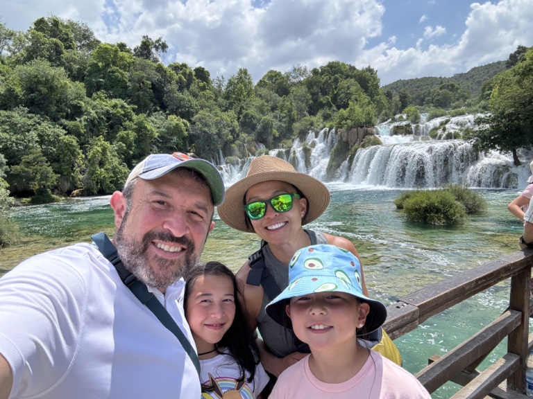 A family selfie in front of a tiered waterfall