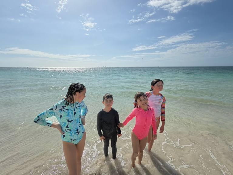 Three children wading at the shore of a lake
