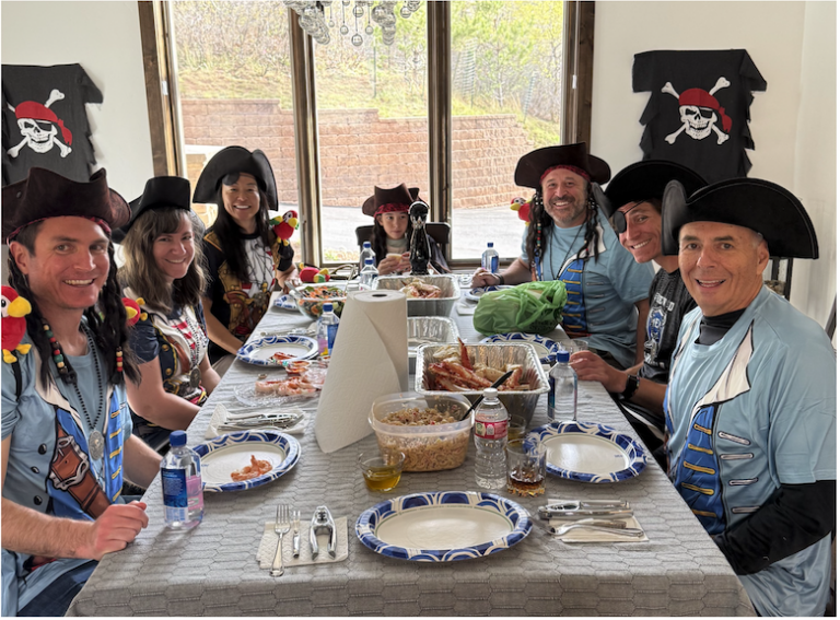 A group in pirate hats seated at a long table for a themed meal