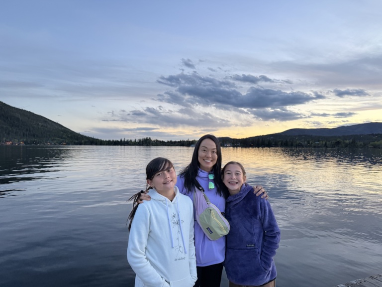 Three girls at the edge of a lake at sunset